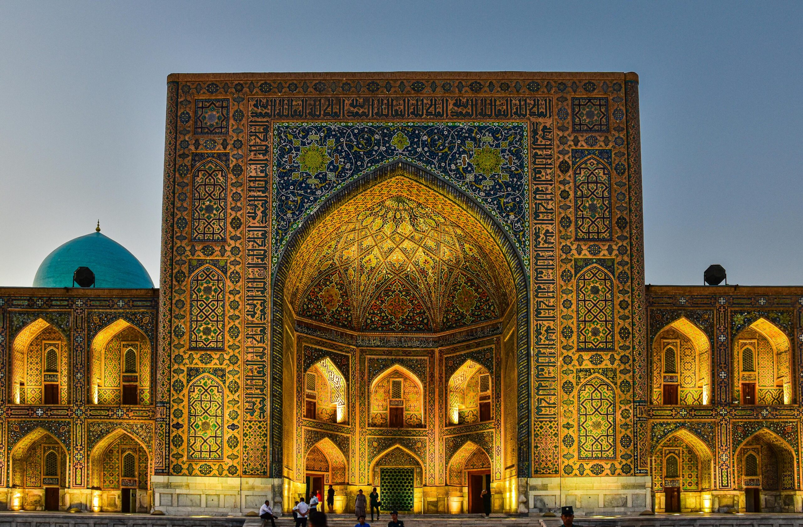 The beautiful Tilya Kori Madrasah in Samarkand, Uzbekistan, illuminated at twilight, showcasing intricate Islamic architecture.