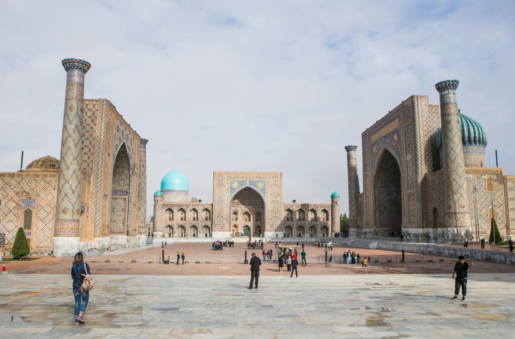 Historic Registan Square with tourists in Samarkand, showcasing stunning Islamic architecture.