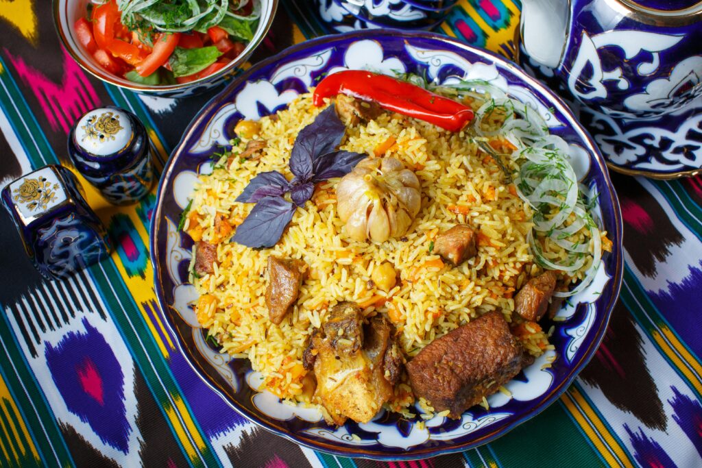 Delicious traditional plov served on an artistic plate with vegetables and herbs.