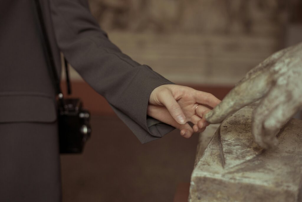 Close-up of a woman gently touching a stone sculpture indoors.