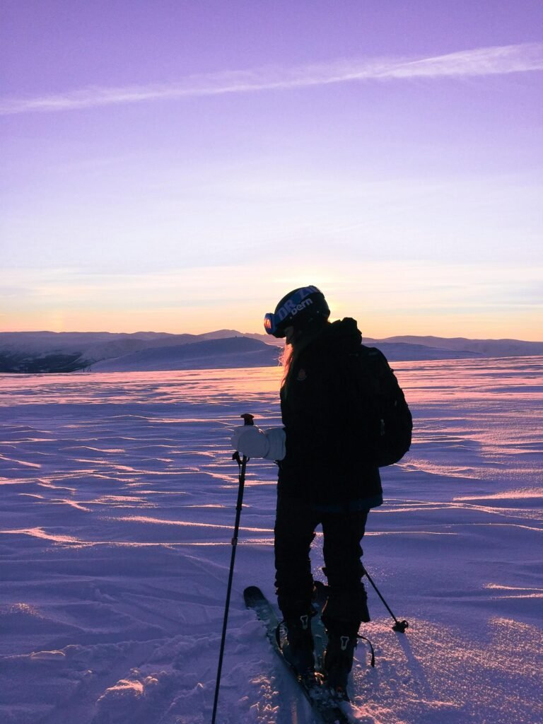 A skier explores the snowy landscapes of Norway during a stunning sunset.
