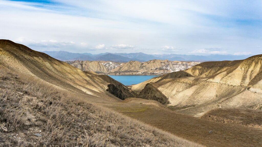 Breathtaking view of arid hills and a serene lake in Talas Region, Kyrgyzstan.