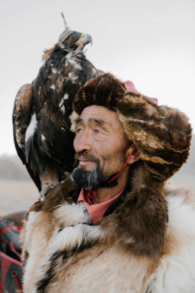 Portrait of a traditional eagle hunter with a majestic bird perched on his arm, showcasing cultural heritage.