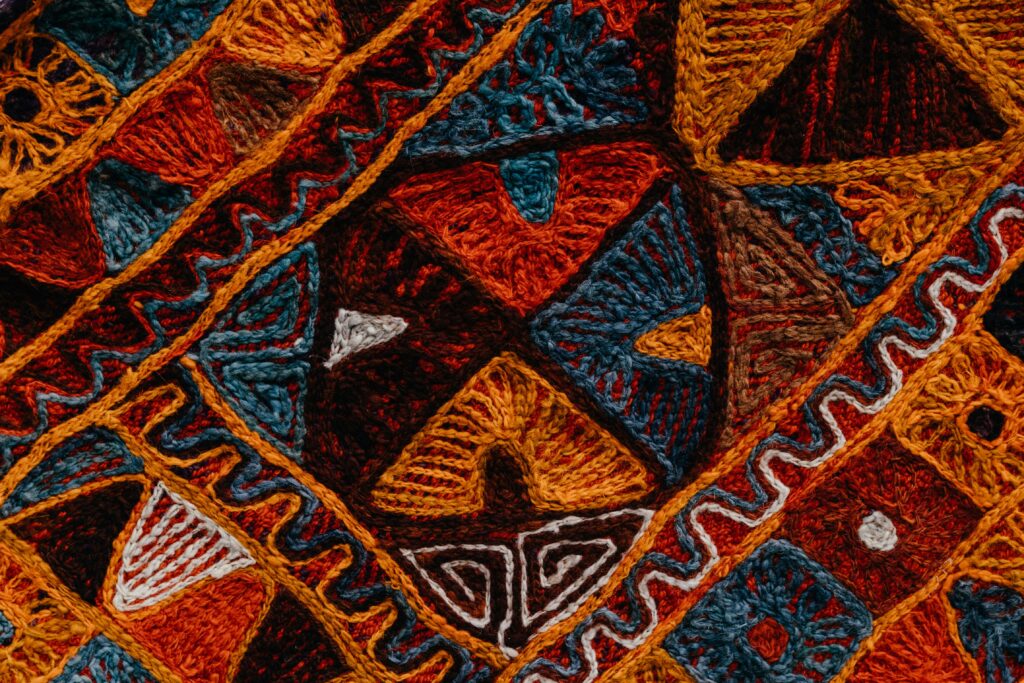 Intricate colorful carpet texture with artistic patterns in detailed close-up view.