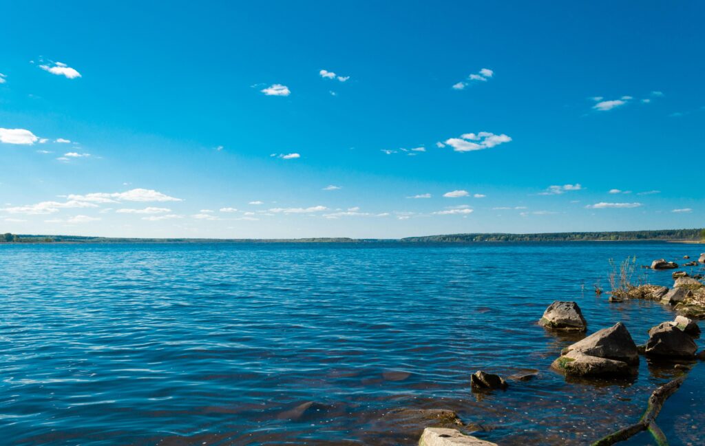 Serene view of a blue lake with rocky shore under a clear blue sky, ideal for nature lovers.
