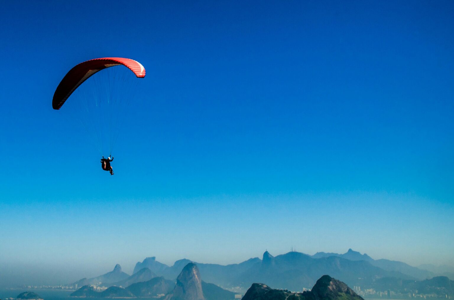 A paraglider flies high above a picturesque mountain range, showcasing freedom and adventure.