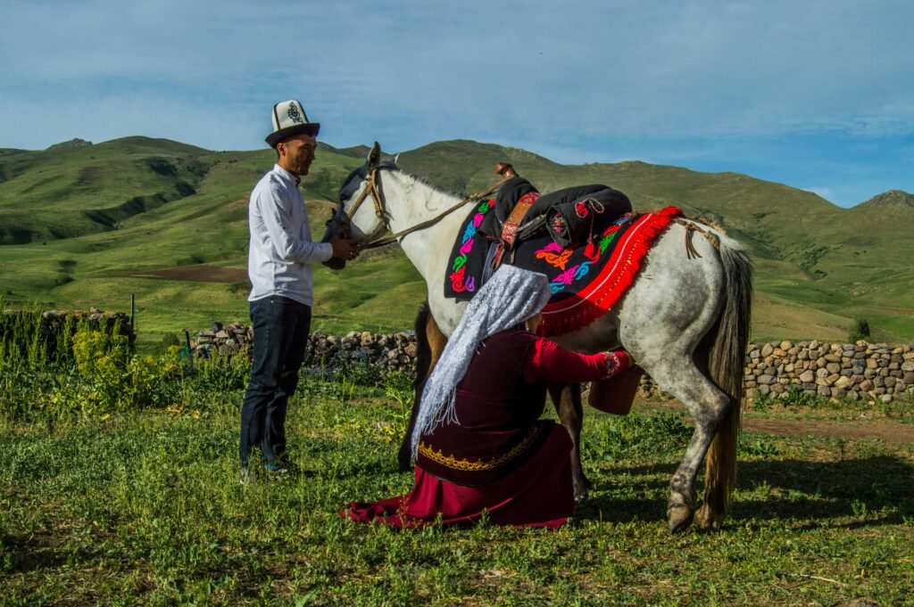 People in traditional dress preparing a horse in rural Ulupamir, Türkiye.