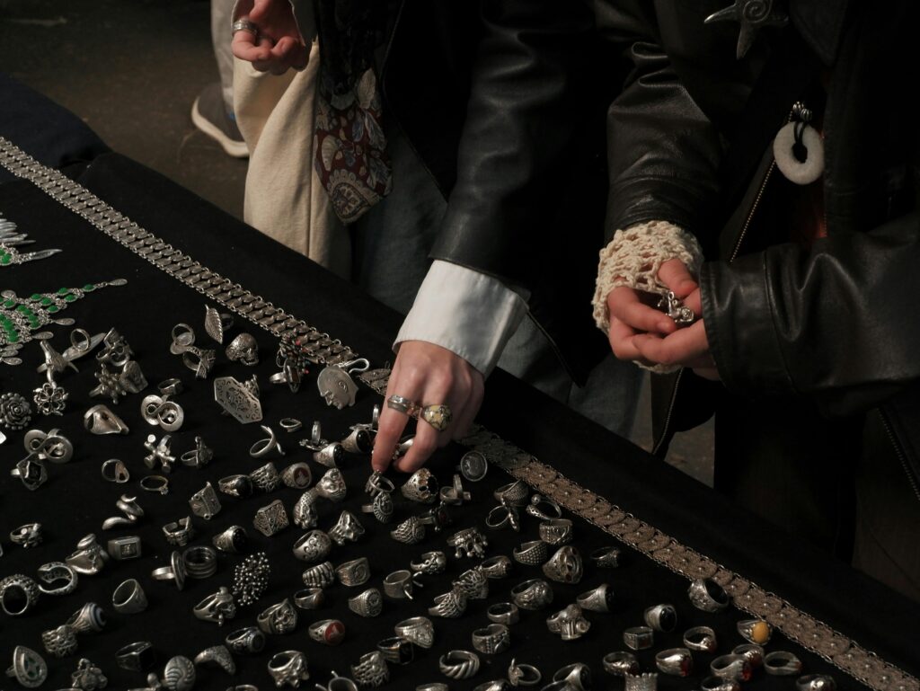 Hands browsing vintage rings at a market stall in Istanbul, showcasing various silver jewelry pieces.