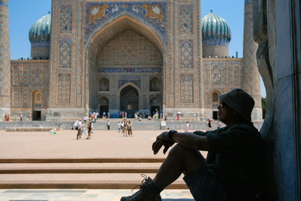A traveler enjoys a moment of pause at a historic Samarkand landmark, framed by intricate architecture.
