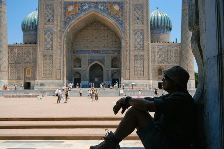 A traveler enjoys a moment of pause at a historic Samarkand landmark, framed by intricate architecture.