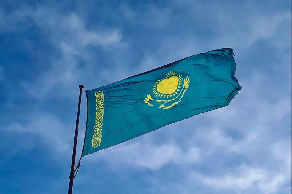 The national flag of Kazakhstan waving against a clear blue sky in Konaev, Almaty Region.