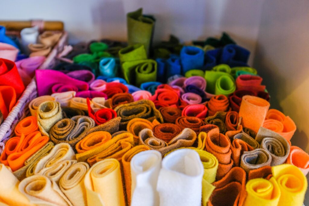 A colorful assortment of rolled felt fabric pieces in various hues, perfect for arts and crafts for kalpaks