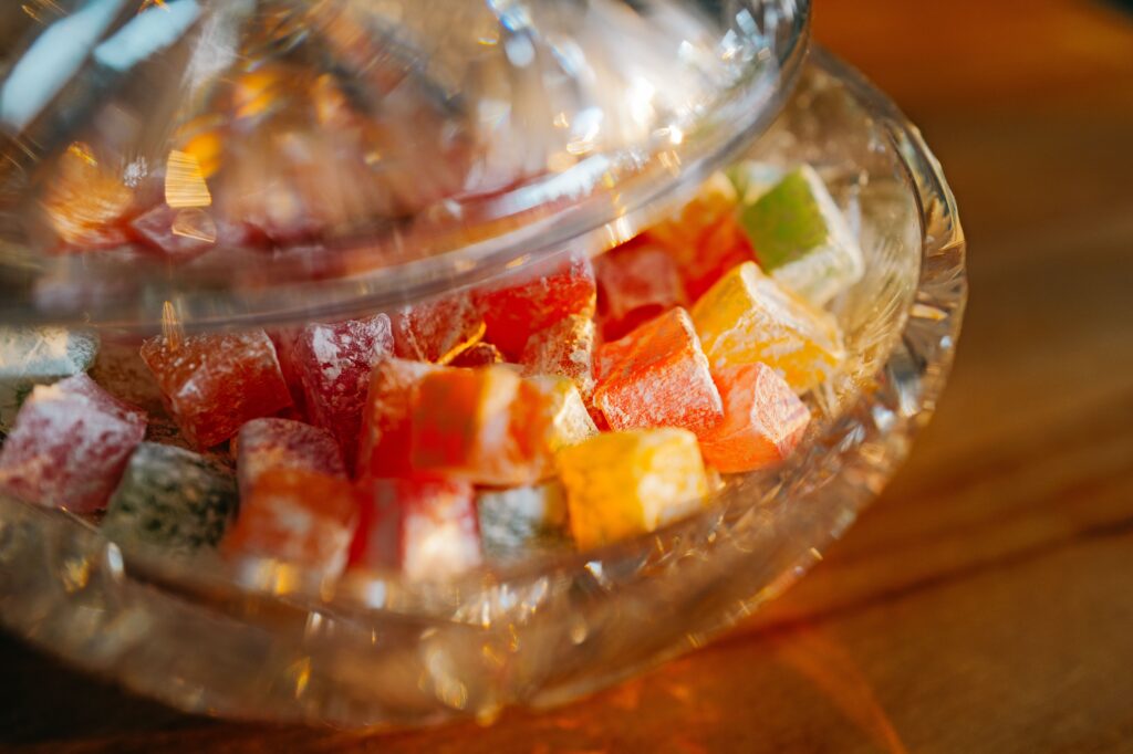 A vibrant selection of Turkish delight candies in a glass dish, illuminated by warm light.