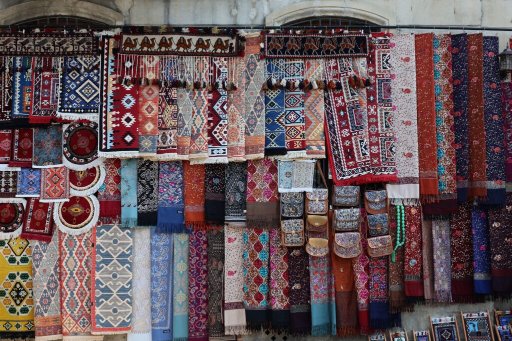 A vibrant collection of traditional carpets and textiles on display, showcasing intricate patterns and rich colors.