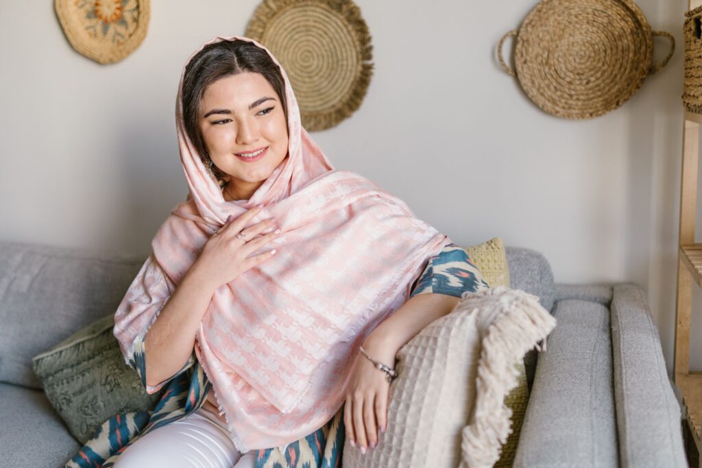 Elegant woman with headscarf smiling indoors, celebrating Nowruz.