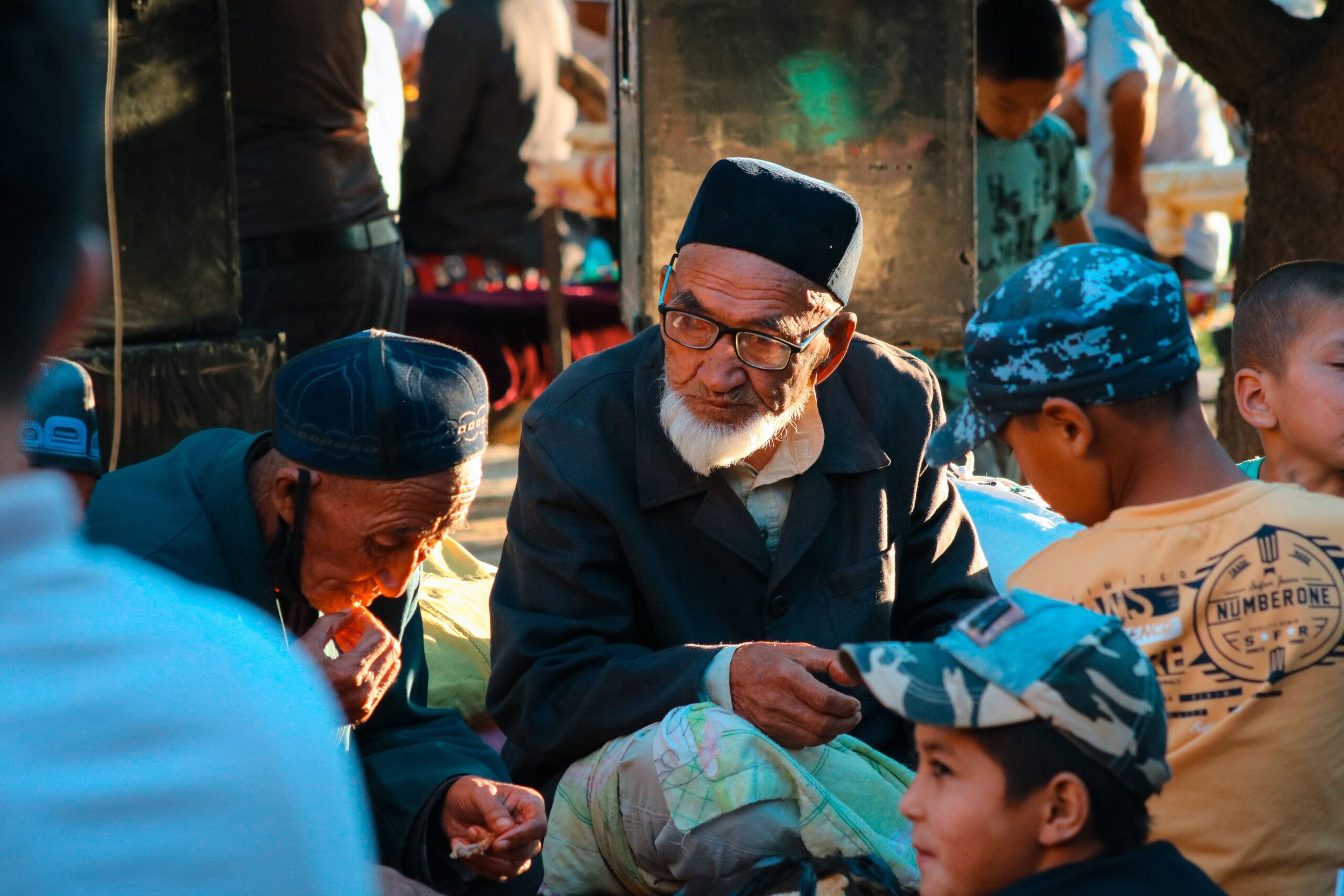 A vibrant market scene in Uzbekistan showing generations of men bonding outdoors.