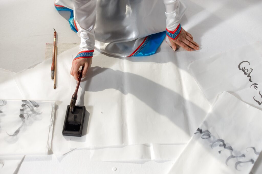 An artistic display of traditional calligraphy using a brush and ink, featuring graceful hand movements.