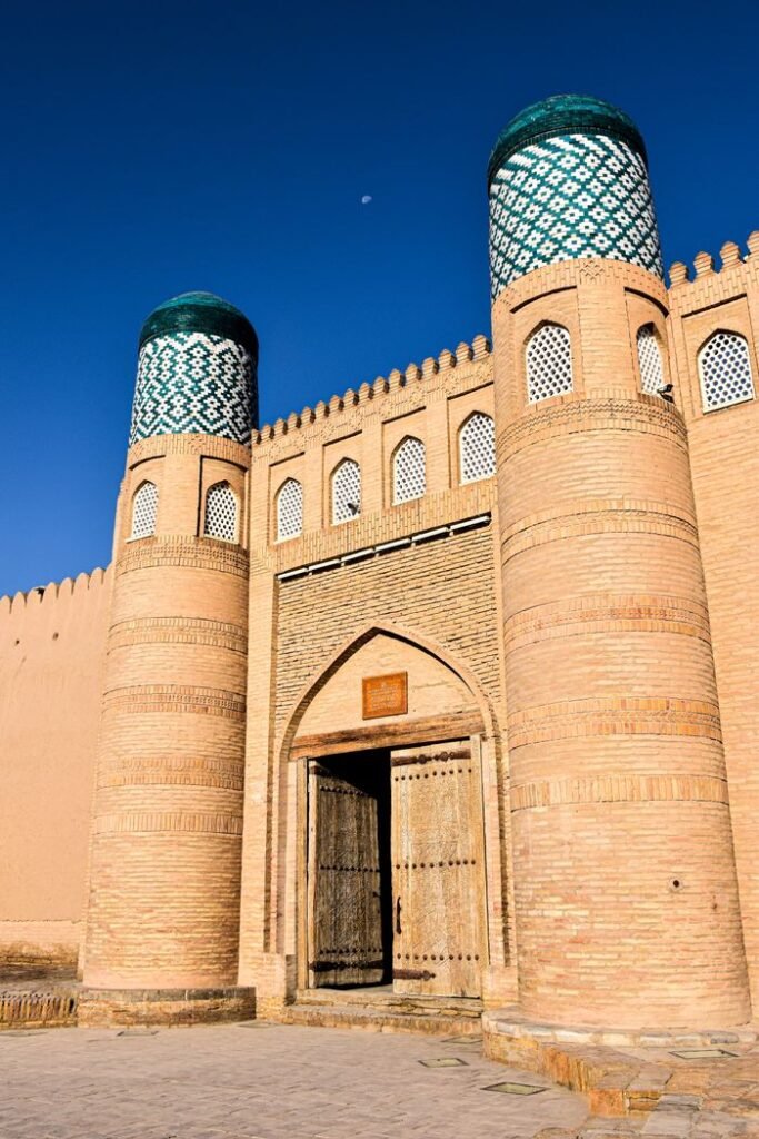 Low angle view of the Kunya-Ark Fortress entrance against a clear blue sky in Khiva, Uzbekistan.