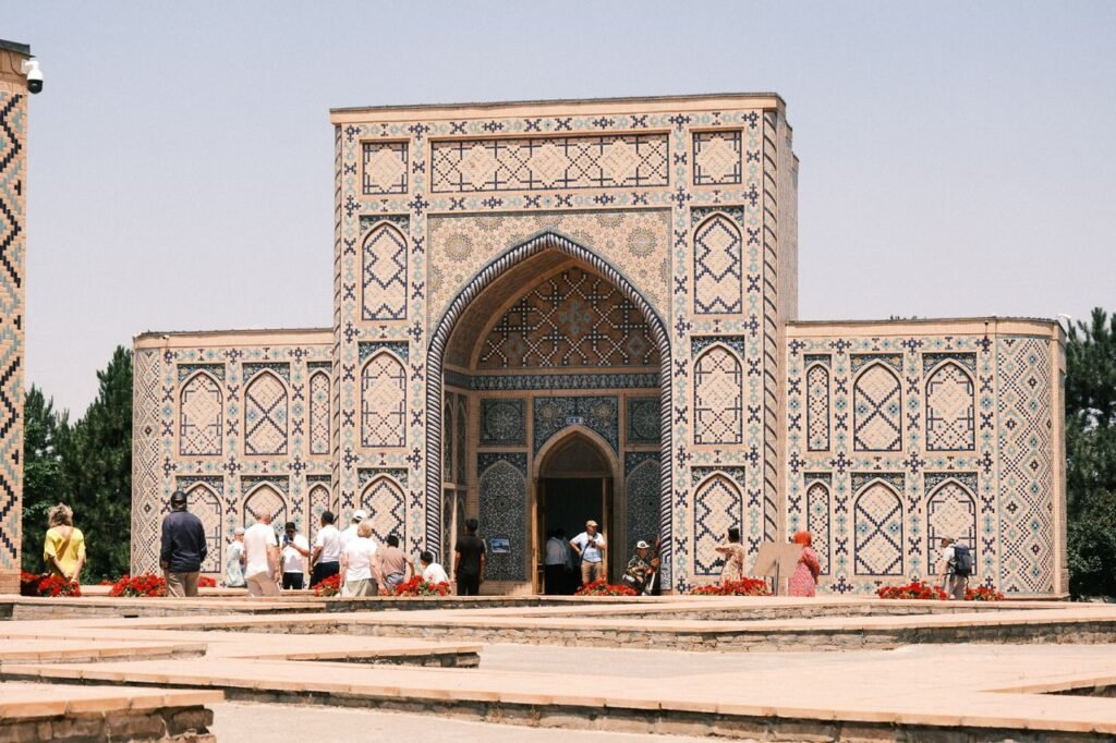 Beautiful historical mausoleum with intricate tilework and tourists exploring outside on a sunny day.