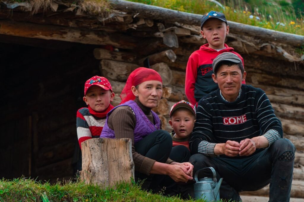 A family gathering outside a rustic home in Yili, Xinjiang, China, highlighting togetherness and local culture.